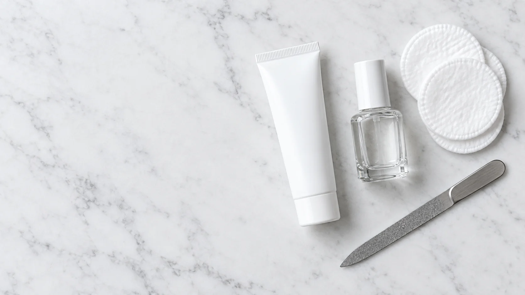 An unbranded ingrown toenail softener tube, antiseptic, cotton pads and a nail file on a marble surface